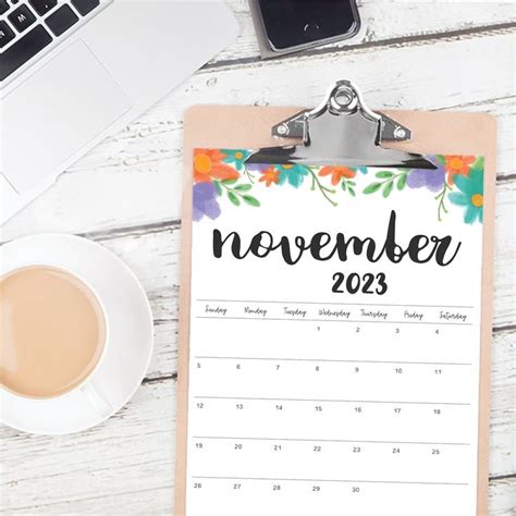 a clipboard with a calendar on it next to a cup of coffee and a laptop