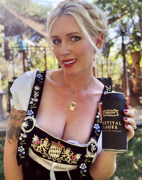 a woman with tattoos holding a beer in her right hand and smiling at ...
